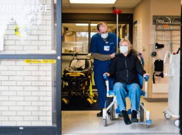MultiCare provider guiding patient in a wheelchair out of the emergency department