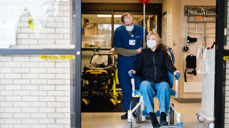 MultiCare provider guiding patient in a wheelchair out of the emergency department