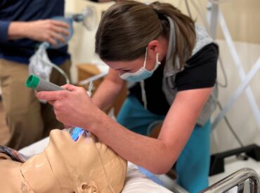 Health care worker performs procedure on simulation manikin
