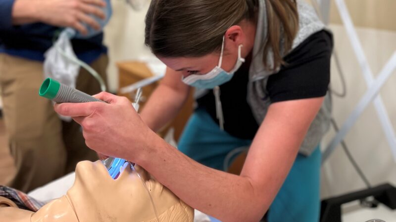 Health care worker performs procedure on simulation manikin
