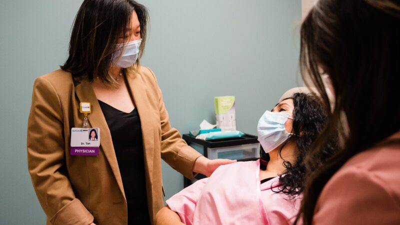 Clinician in mask helps patient